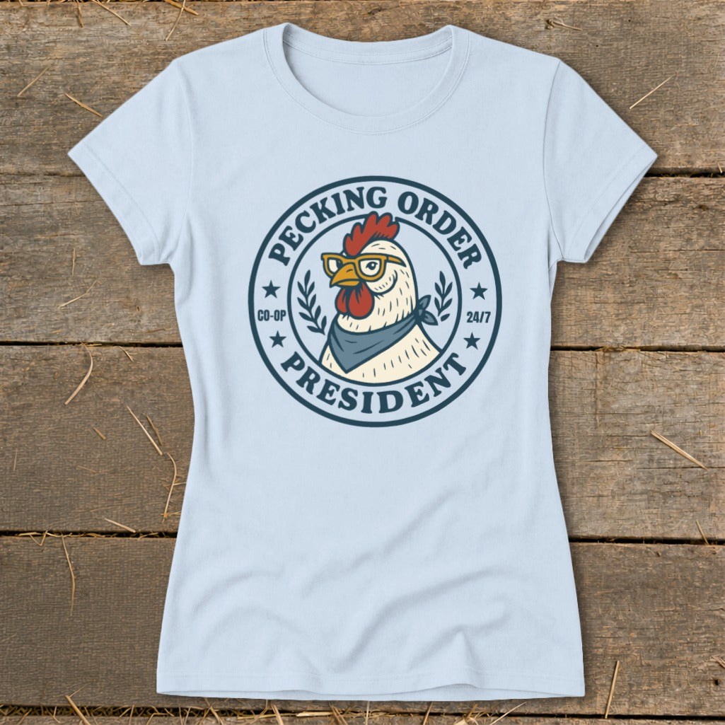 Light blue t-shirt with a circular graphic of a rooster wearing glasses and a bandana, reading "Pecking Order President"