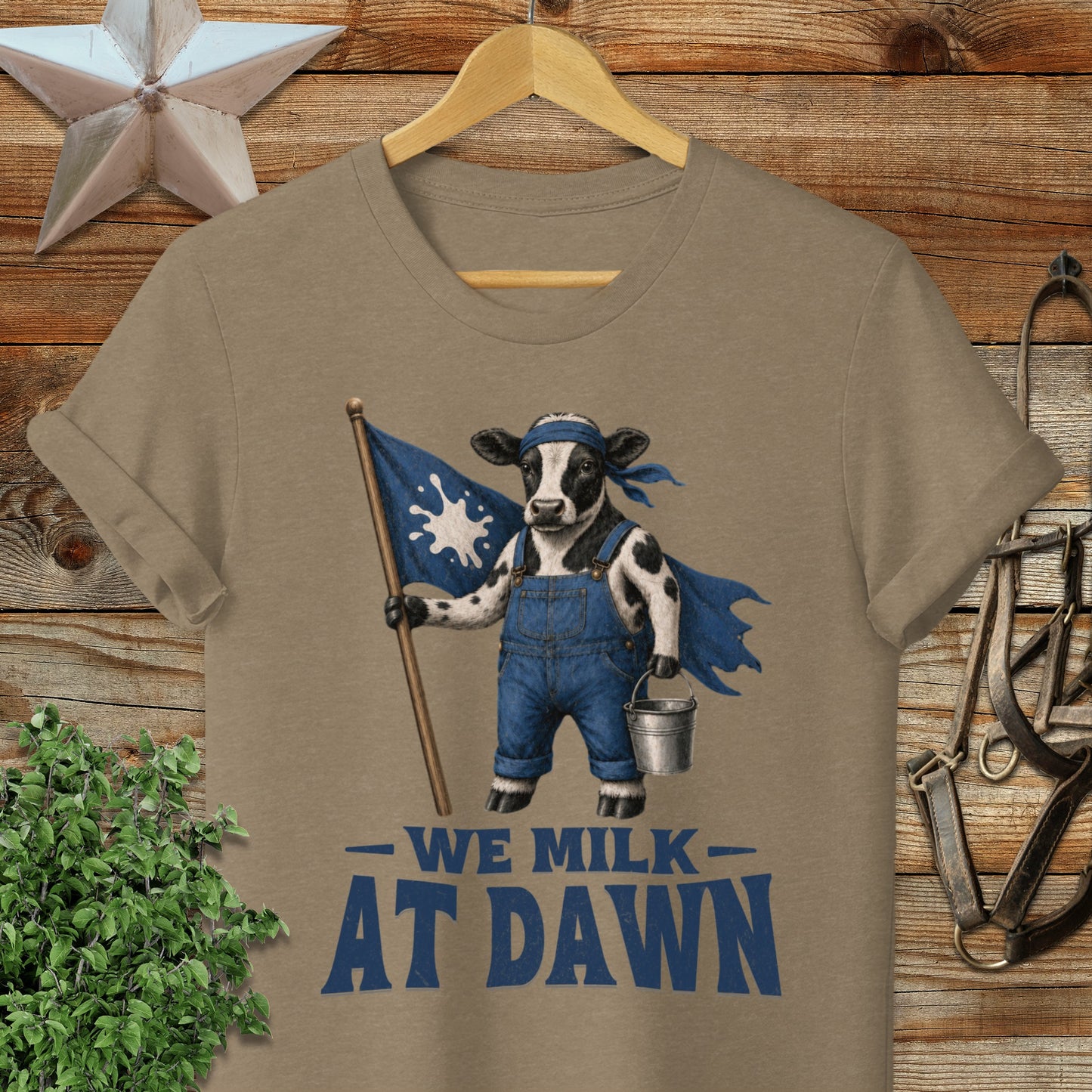 Cow in overalls holding flag that says "We Milk At Dawn."