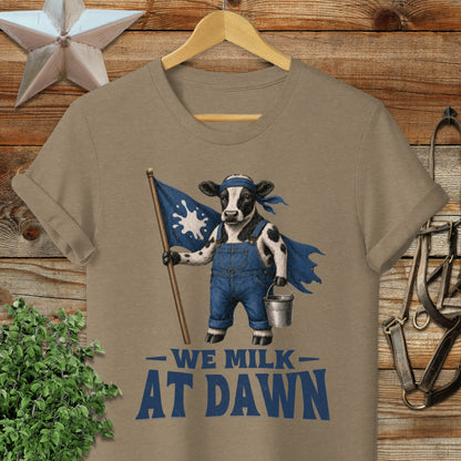 Cow in overalls holding flag that says "We Milk At Dawn."