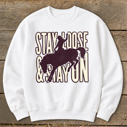 White sweatshirt with "STAY LOOSE & STAY ON" and bucking bronco graphic.