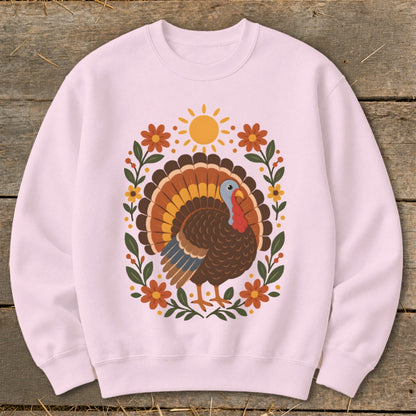 Pink sweatshirt with a cartoon turkey, floral wreath, and sun graphic.