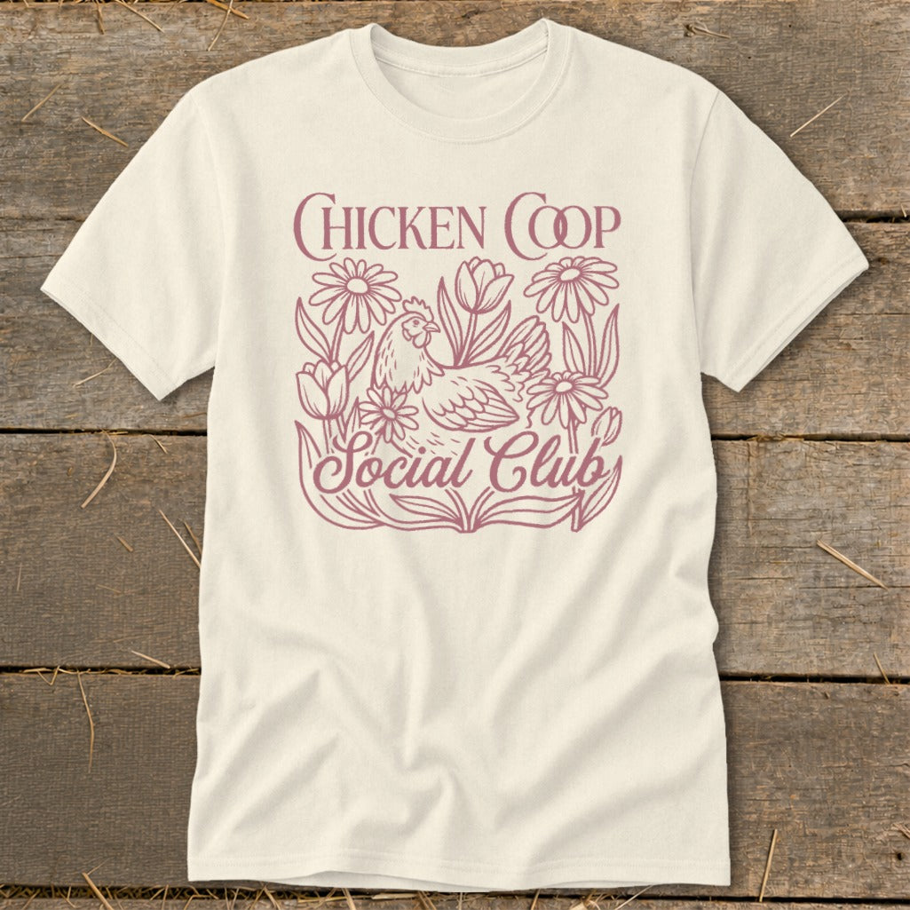 Cream t-shirt with a pink line art design of a chicken and flowers, text reads "CHICKEN COOP Social Club".