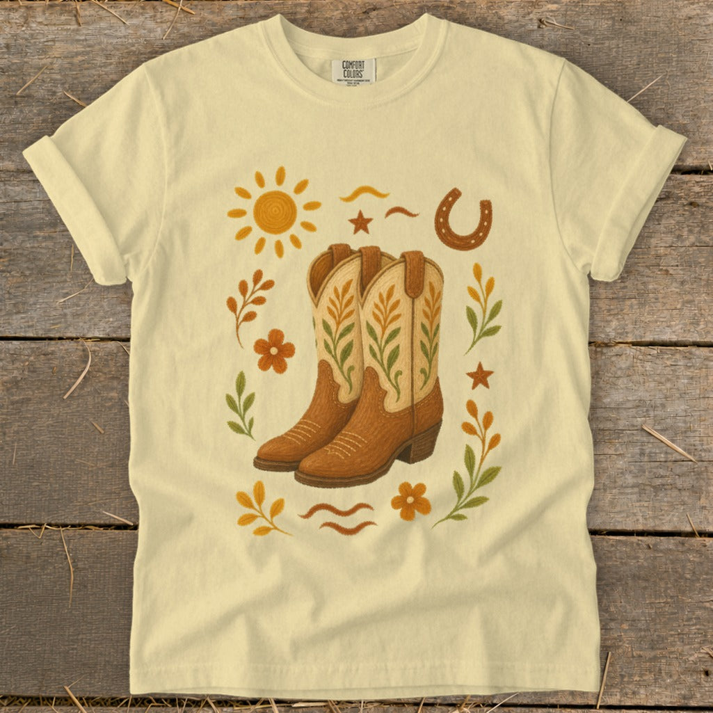 Yellow t-shirt with cowboy boots, sun, horseshoe, and floral graphic design.