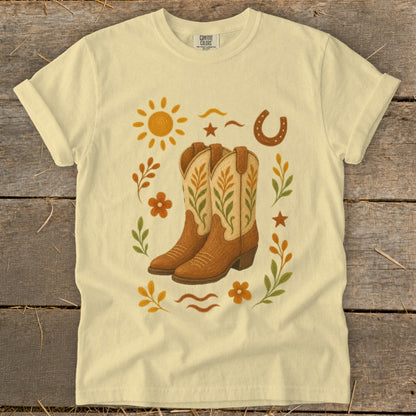 Yellow t-shirt with cowboy boots, sun, horseshoe, and floral graphic design.