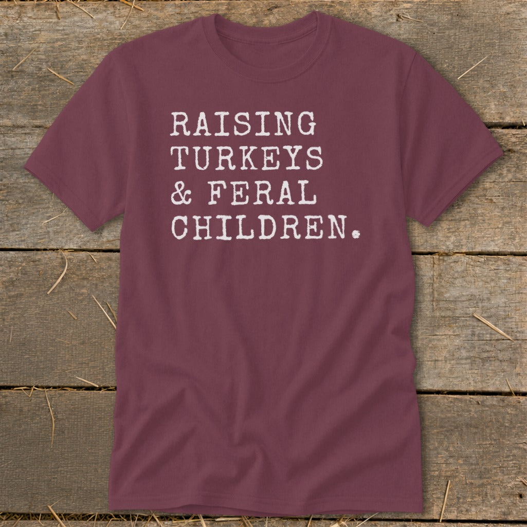 Maroon t-shirt with white text: "RAISING TURKEYS & FERAL CHILDREN."
