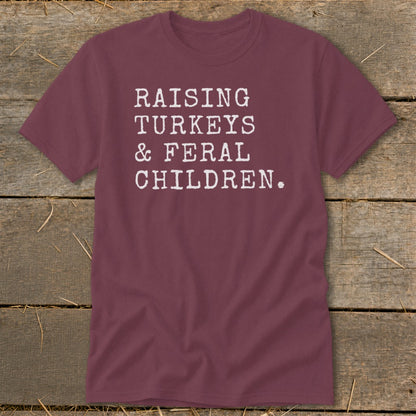 Maroon t-shirt with white text: "RAISING TURKEYS & FERAL CHILDREN."