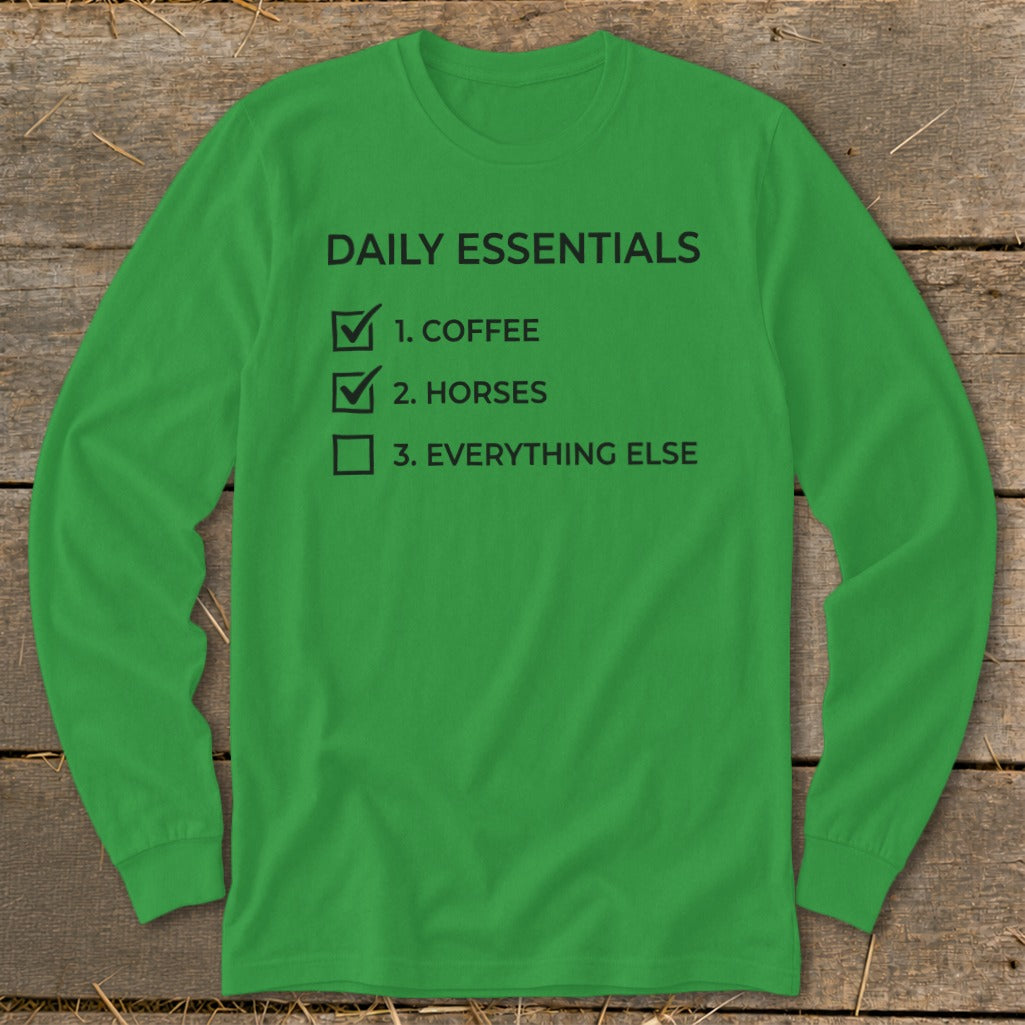 Green long-sleeve shirt with black text: "DAILY ESSENTIALS", "1. COFFEE", "2. HORSES", "3. EVERYTHING ELSE".