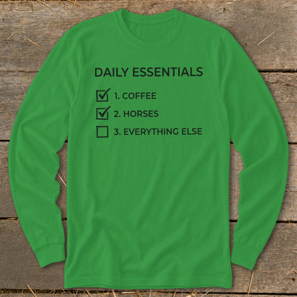 Green long-sleeve shirt with black text: "DAILY ESSENTIALS", "1. COFFEE", "2. HORSES", "3. EVERYTHING ELSE".