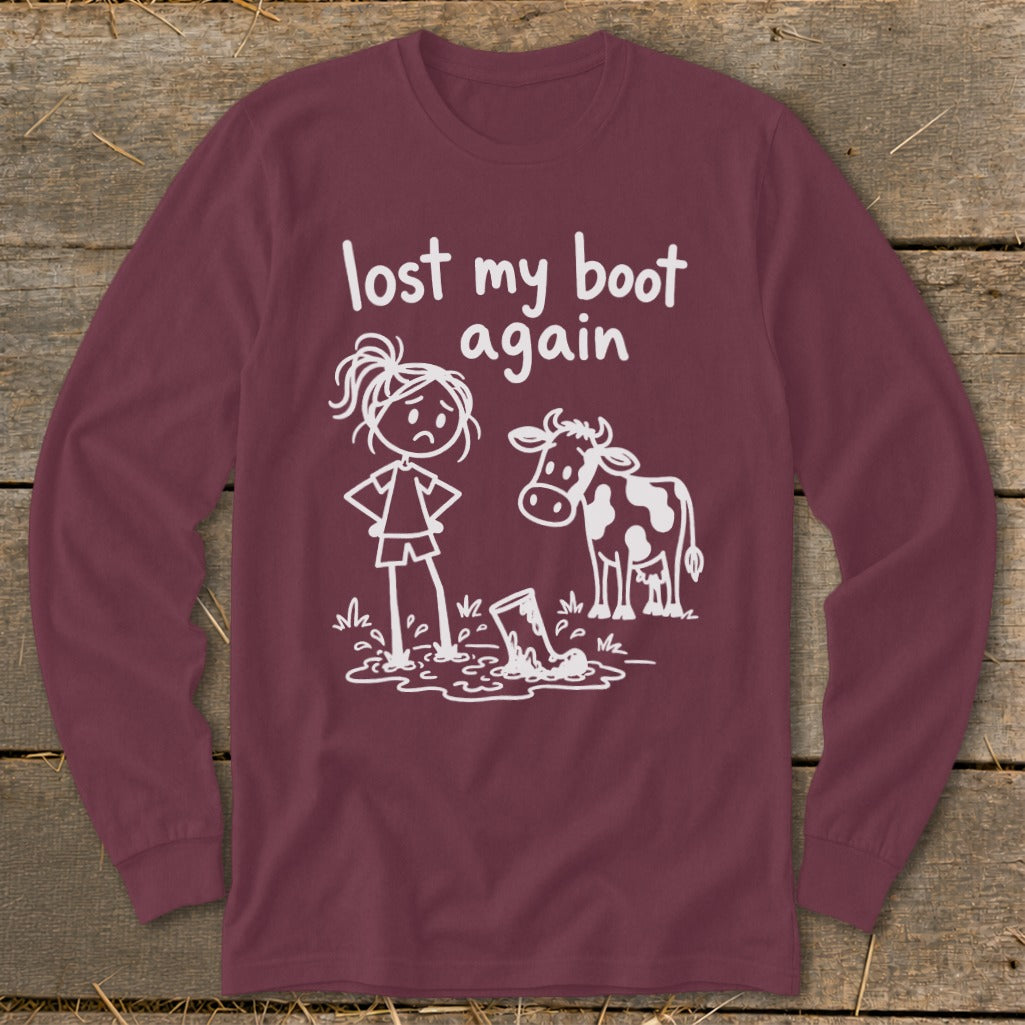 Maroon long-sleeve t-shirt with a white stick-figure graphic of a girl and cow looking at a muddy boot, with text reading lost my boot again.
