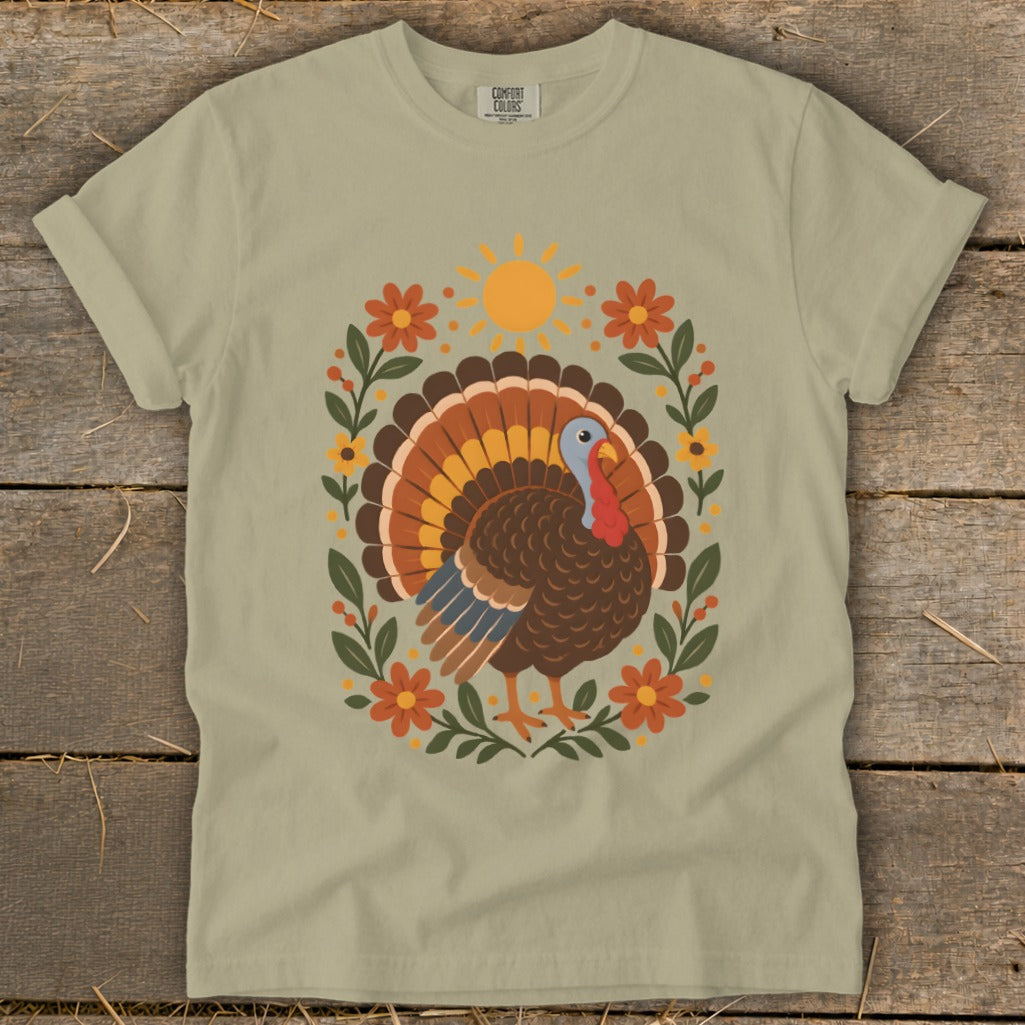Light tan t-shirt with a festive turkey and floral design, "Comfort Colors" tag.