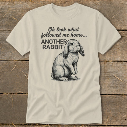 Light beige t-shirt with sketch of rabbit and text "Oh look what followed me home... ANOTHER RABBIT".