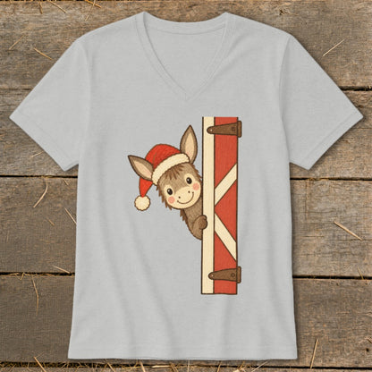 Cartoon donkey wearing Santa hat peeks around barn door on gray t-shirt.