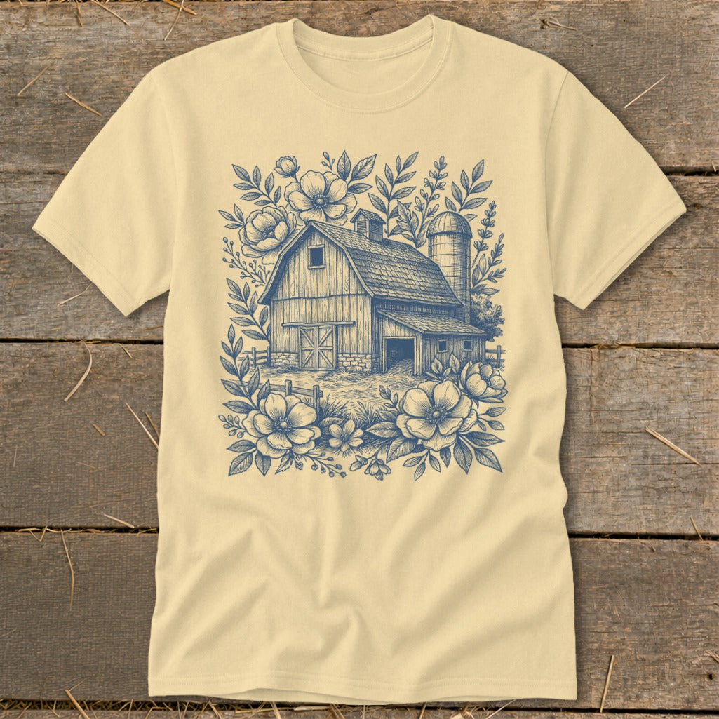 Cream t-shirt with a navy blue barn and floral graphic design.