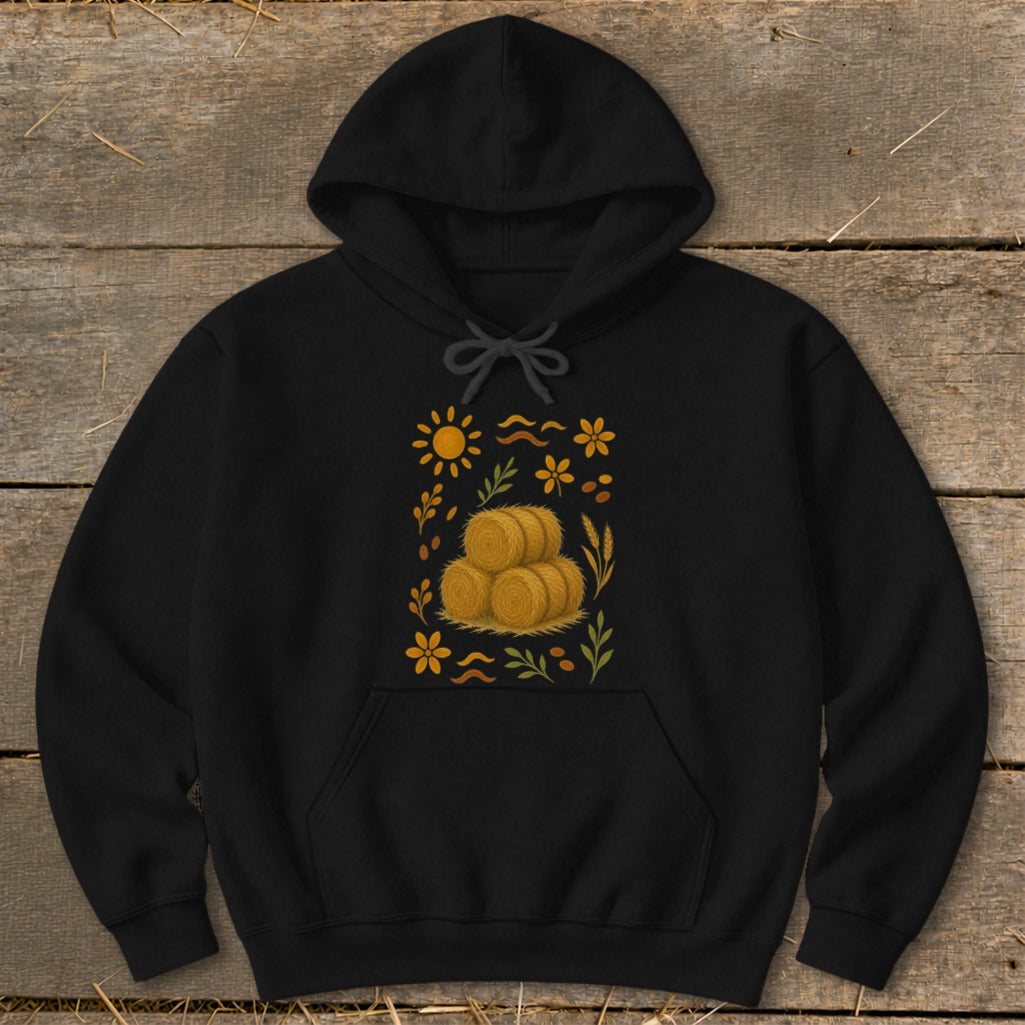Black hoodie with a square graphic featuring hay bales, sun, and flowers.
