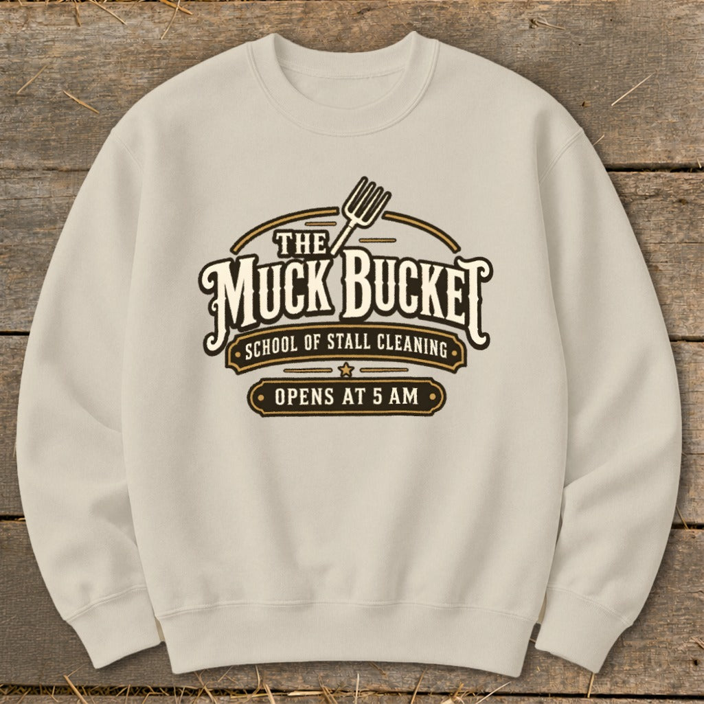 Cream sweatshirt with "The Muck Bucket School of Stall Cleaning Opens at 5 AM" text.