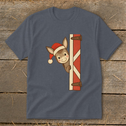 Donkey wearing a Santa hat peeking from behind a red barn door.