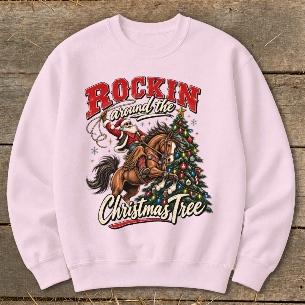 Pink sweatshirt with Santa riding a horse next to a Christmas tree.