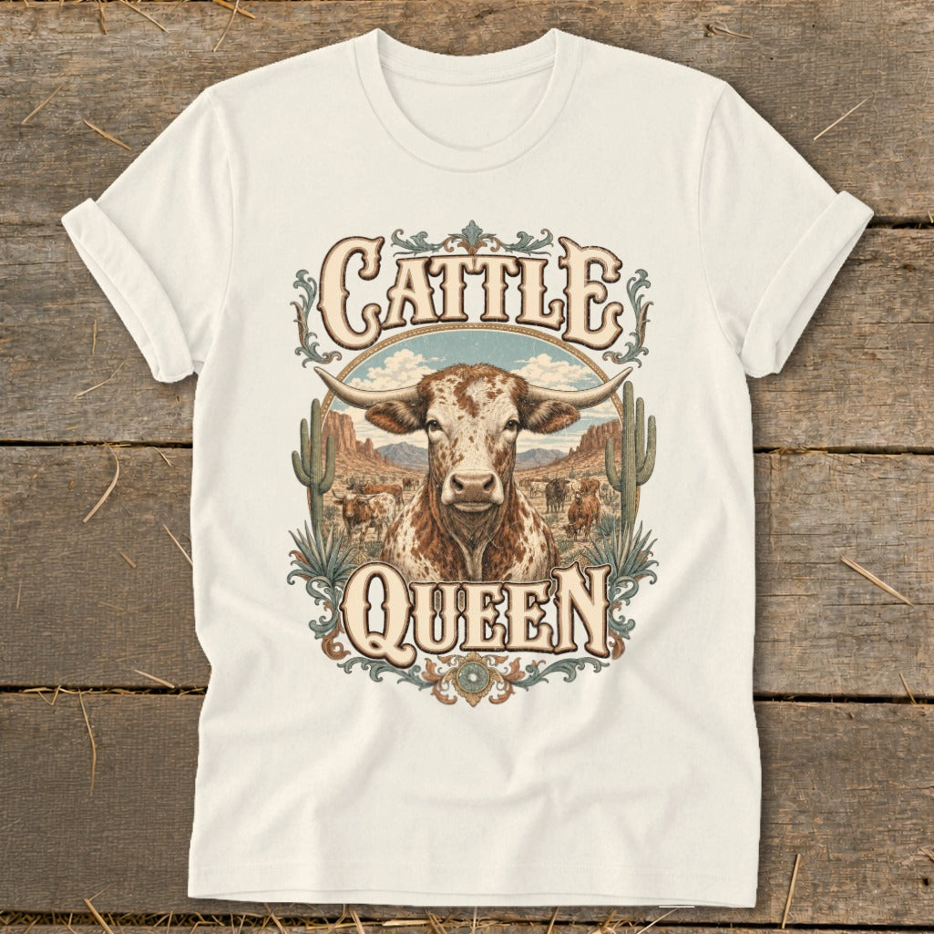 White t-shirt graphic with a longhorn bull, desert, and "Cattle Queen" text.
