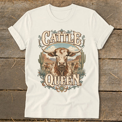 White t-shirt graphic with a longhorn bull, desert, and "Cattle Queen" text.