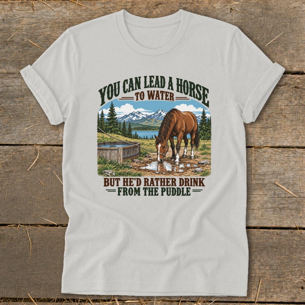 A light gray t-shirt featuring a graphic of a horse drinking from a puddle with humorous text.