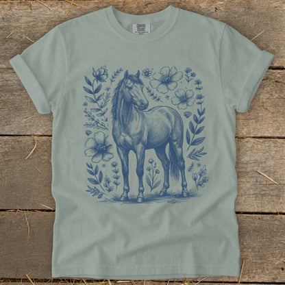 Light blue t-shirt with a blue sketch of a horse surrounded by floral elements.