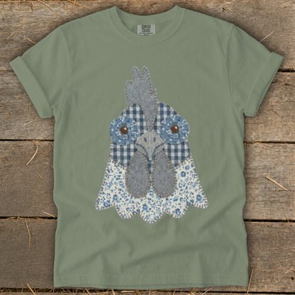 Sage green t-shirt with a blue and white fabric chicken head applique.