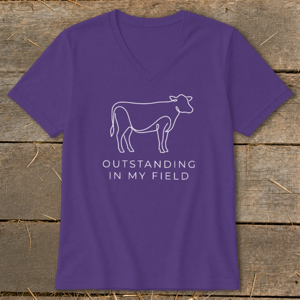 Purple v-neck t-shirt with white outline of a cow and text "OUTSTANDING IN MY FIELD".