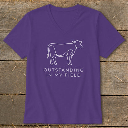 Purple v-neck t-shirt with white outline of a cow and text "OUTSTANDING IN MY FIELD".