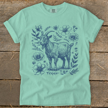 Teal t-shirt with a dark blue illustration of a goat surrounded by flowers.