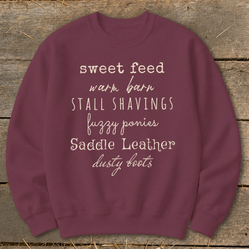 Maroon sweatshirt with text "sweet feed warm barn STALL SHAVINGS fuzzy ponies Saddle Leather dusty boots".