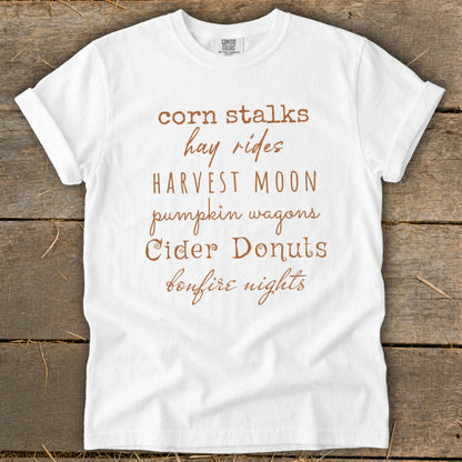 White t-shirt with "corn stalks, hay rides, HARVEST MOON, pumpkin wagons, Cider Donuts, bonfire nights" text.