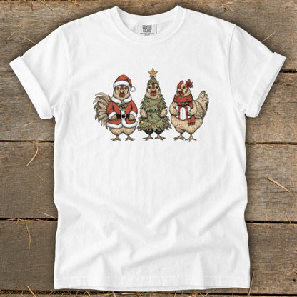 White t-shirt featuring cartoon rooster in Santa suit, a Christmas tree, and chicken with gift.