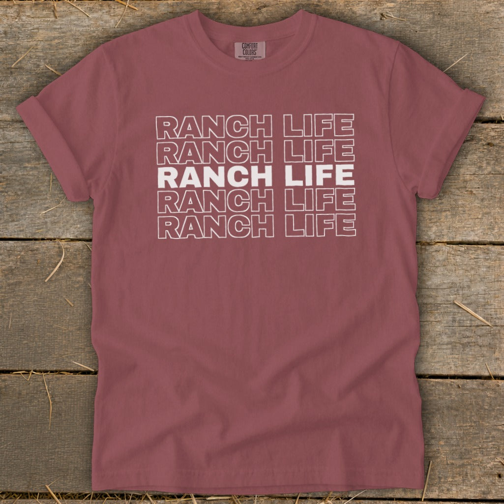 Dusty rose crewneck t-shirt with repeated white outline text reading Ranch Life on a wooden background.