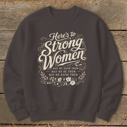 Dark gray sweatshirt with "Here's to Strong Women" text and floral design.
