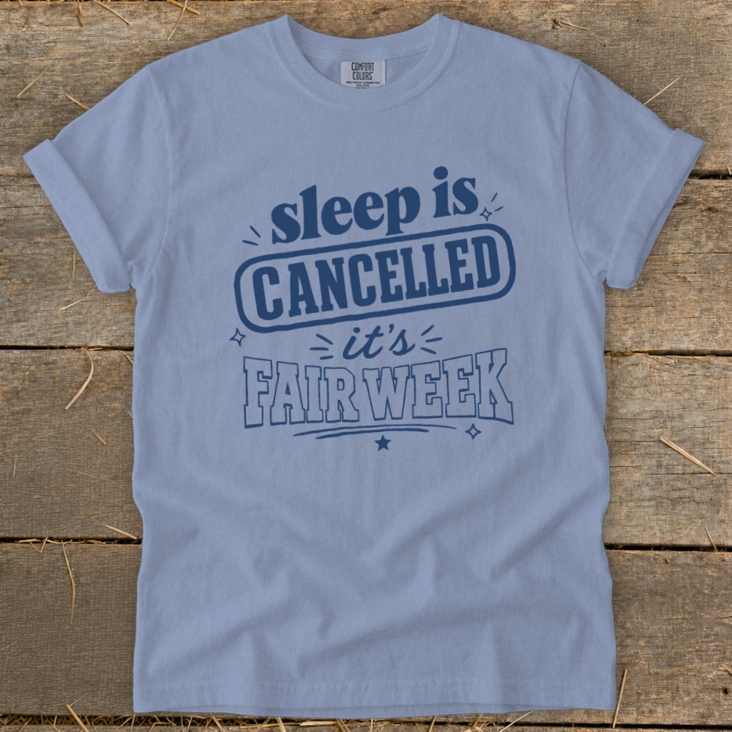 Light blue t-shirt with navy blue text reading "sleep is CANCELLED > it's FAIR WEEK".