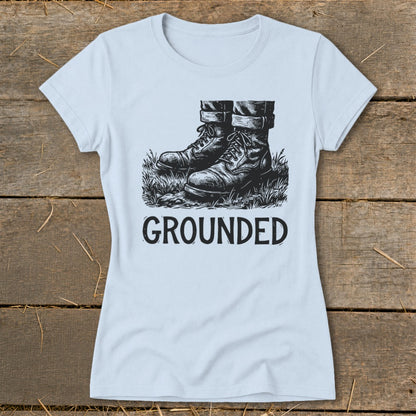 Light blue t-shirt with a black graphic of work boots in grass and the word "GROUNDED".