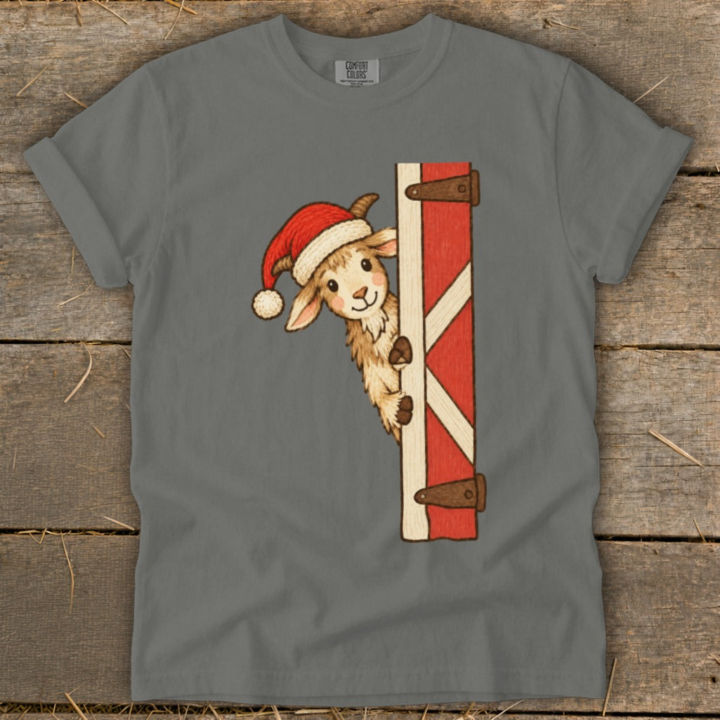 Goat in a Santa hat peeking from behind a red barn door graphic on a gray t-shirt.