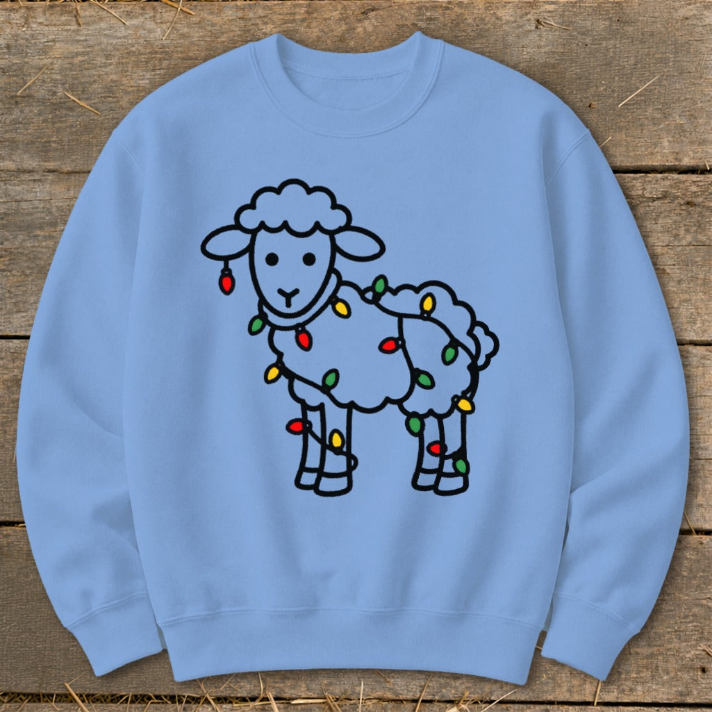 A light blue crewneck sweatshirt featuring a line drawing of a sheep wrapped in colorful Christmas lights.