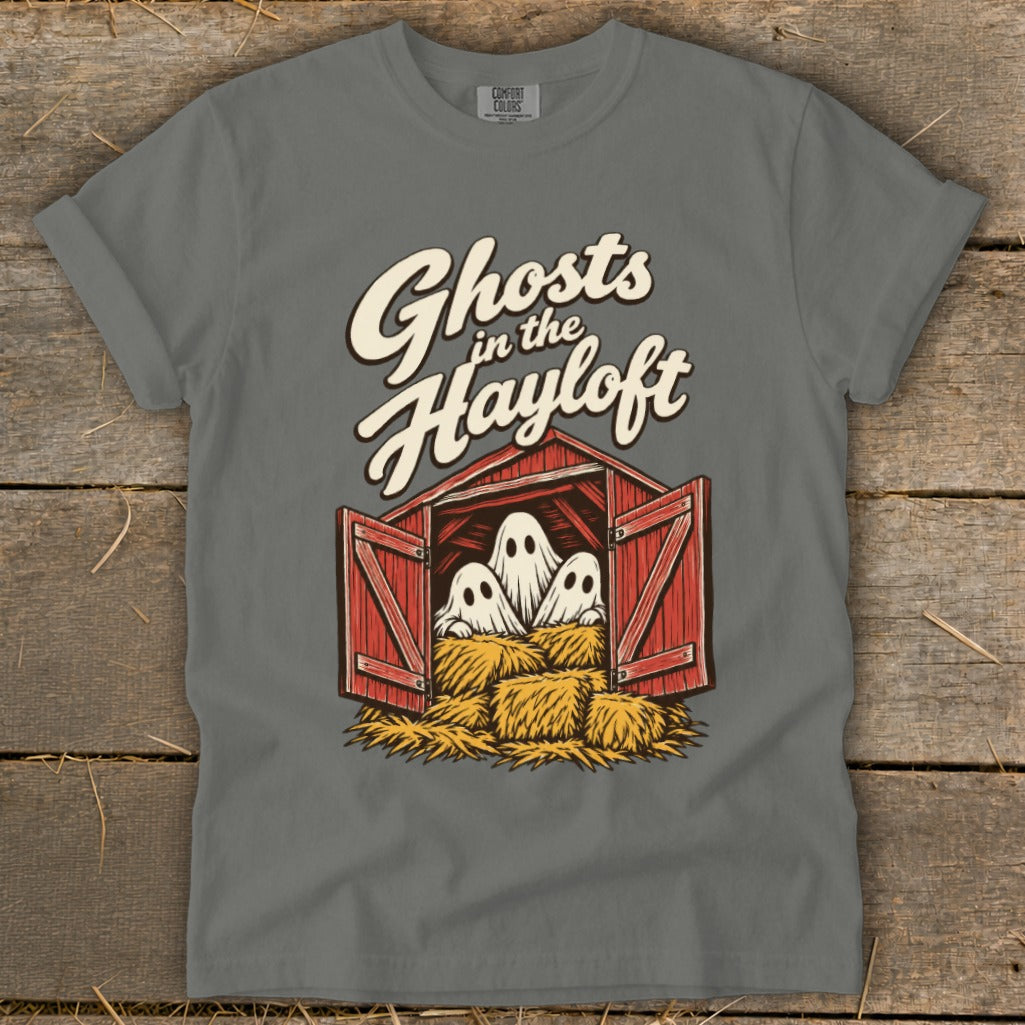 Three cute ghosts peek out from a hayloft above bales of hay.