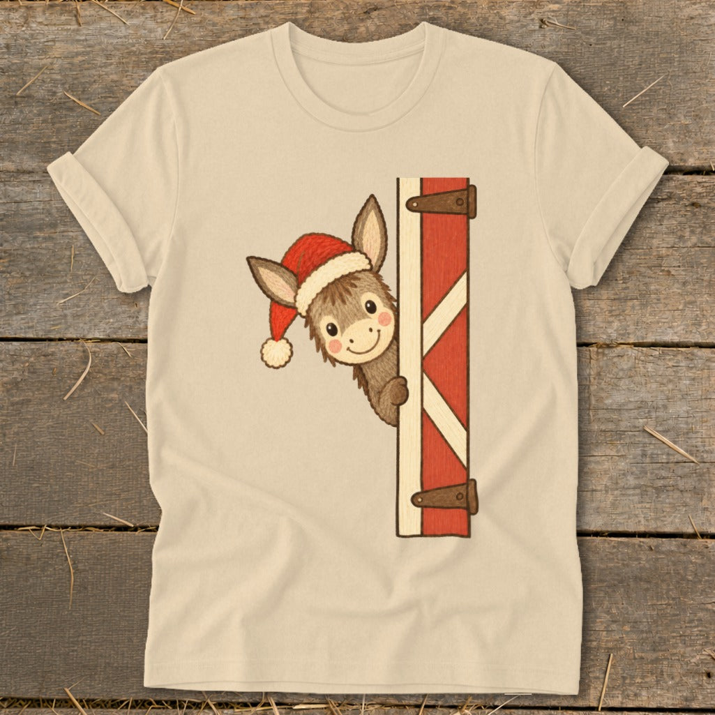 Donkey in Santa hat peeking from behind a red barn door on a tan t-shirt.