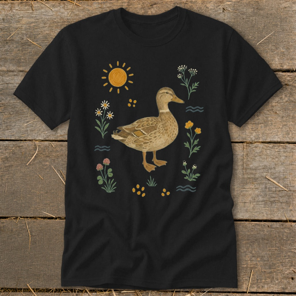 Black t-shirt with a duck surrounded by wildflowers and a sun illustration.