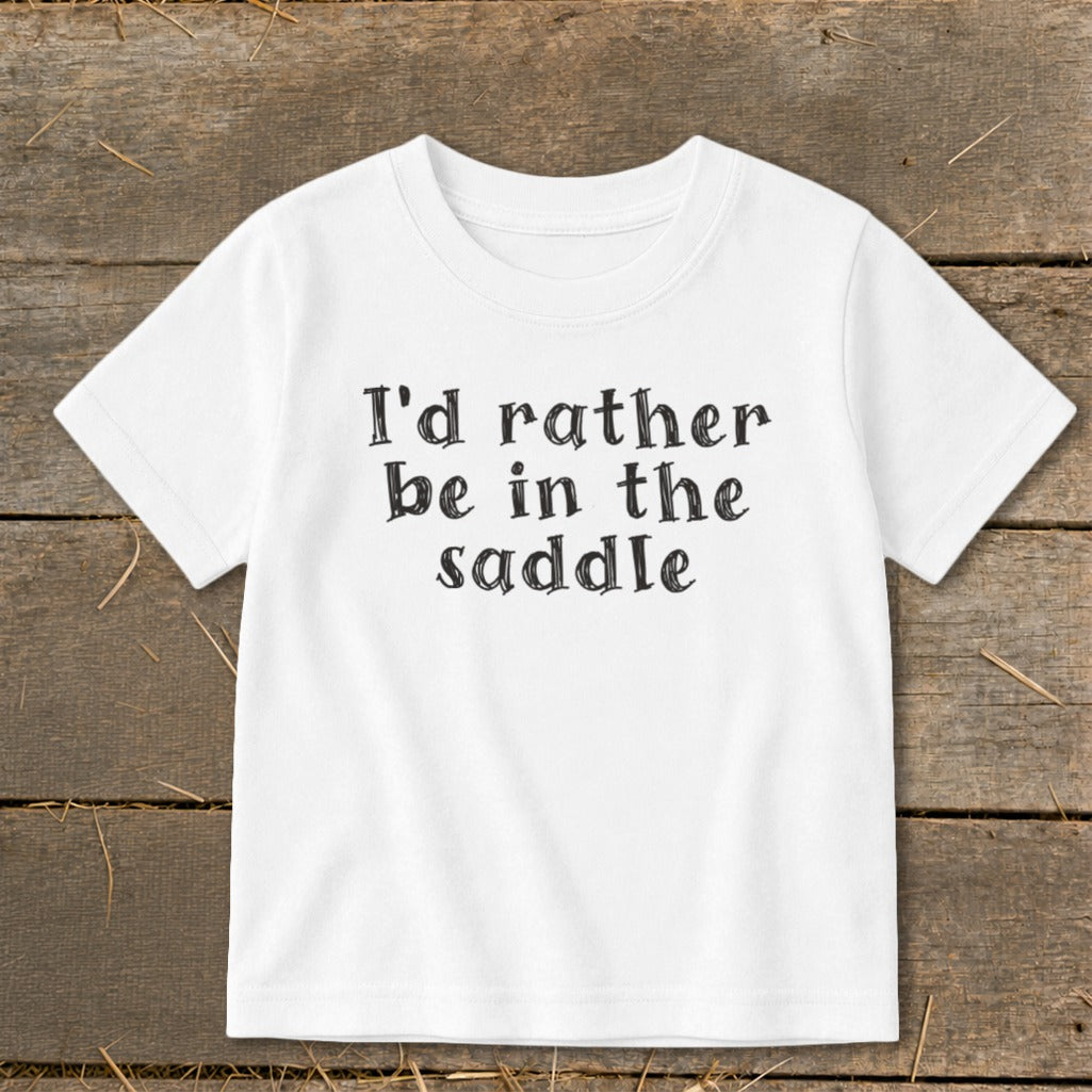 White t-shirt with "I'd rather be in the saddle" text in black font.