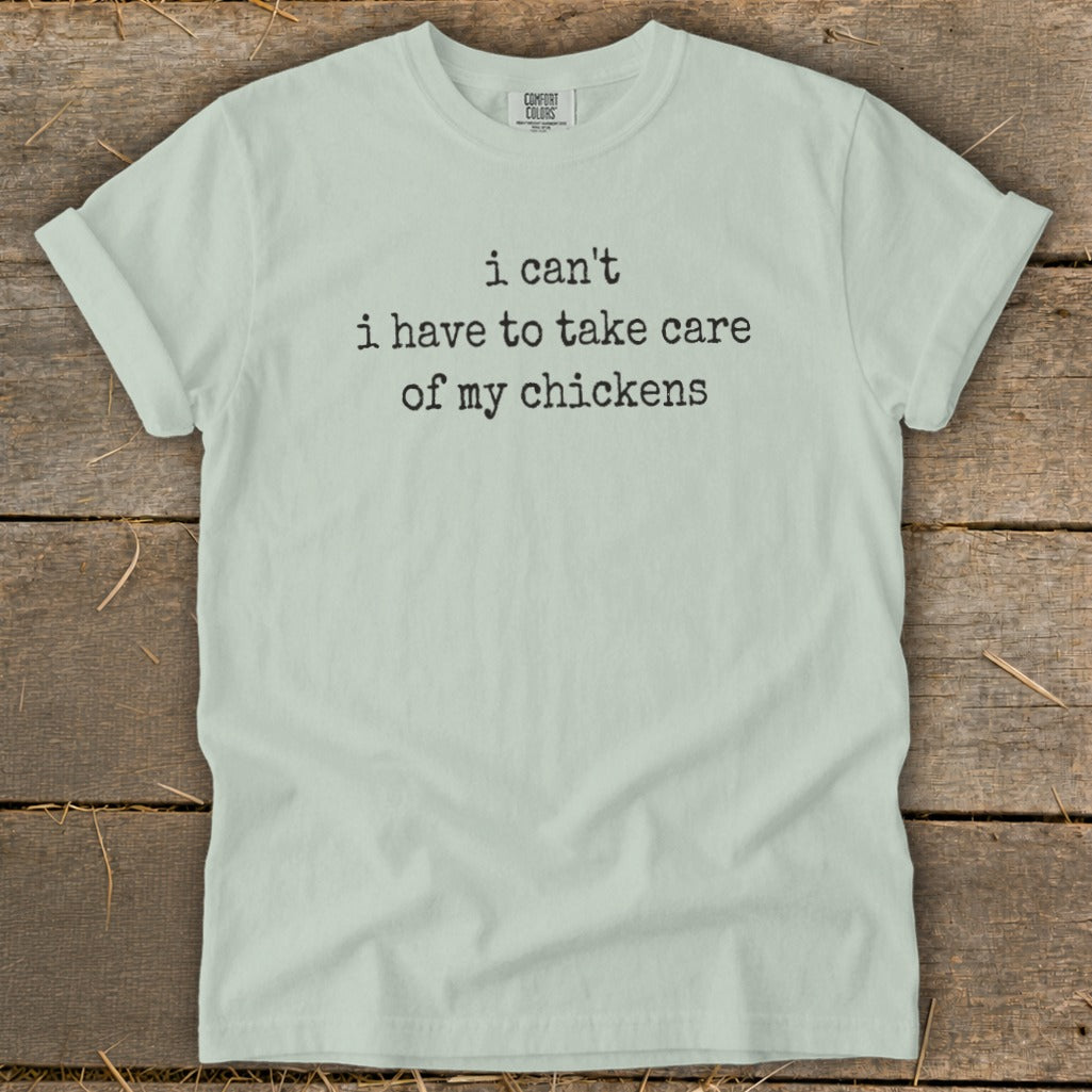 Light green t-shirt with black text reading "i can't i have to take care of my chickens".