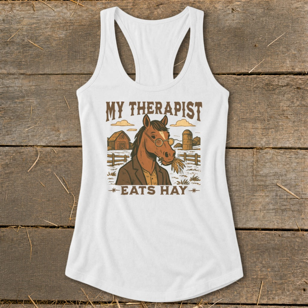 White tank top with illustration of a horse in a suit, text reads "MY THERAPIST EATS HAY".