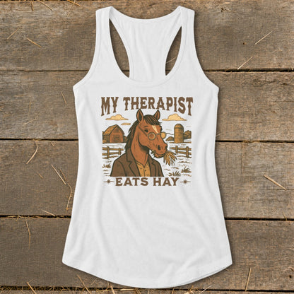 White tank top with illustration of a horse in a suit, text reads "MY THERAPIST EATS HAY".