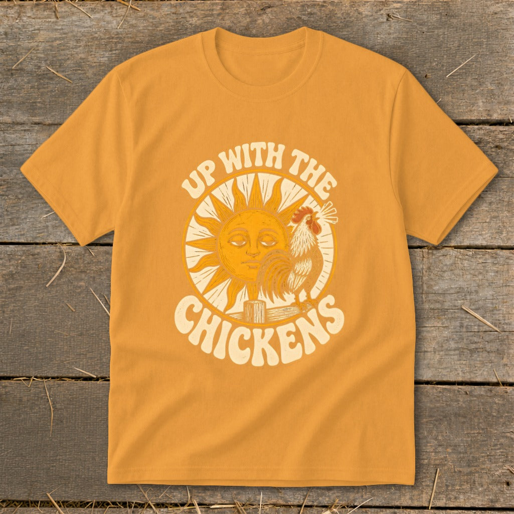 A mustard yellow t-shirt features a retro graphic of a sun, rooster, and the text "Up With the Chickens."