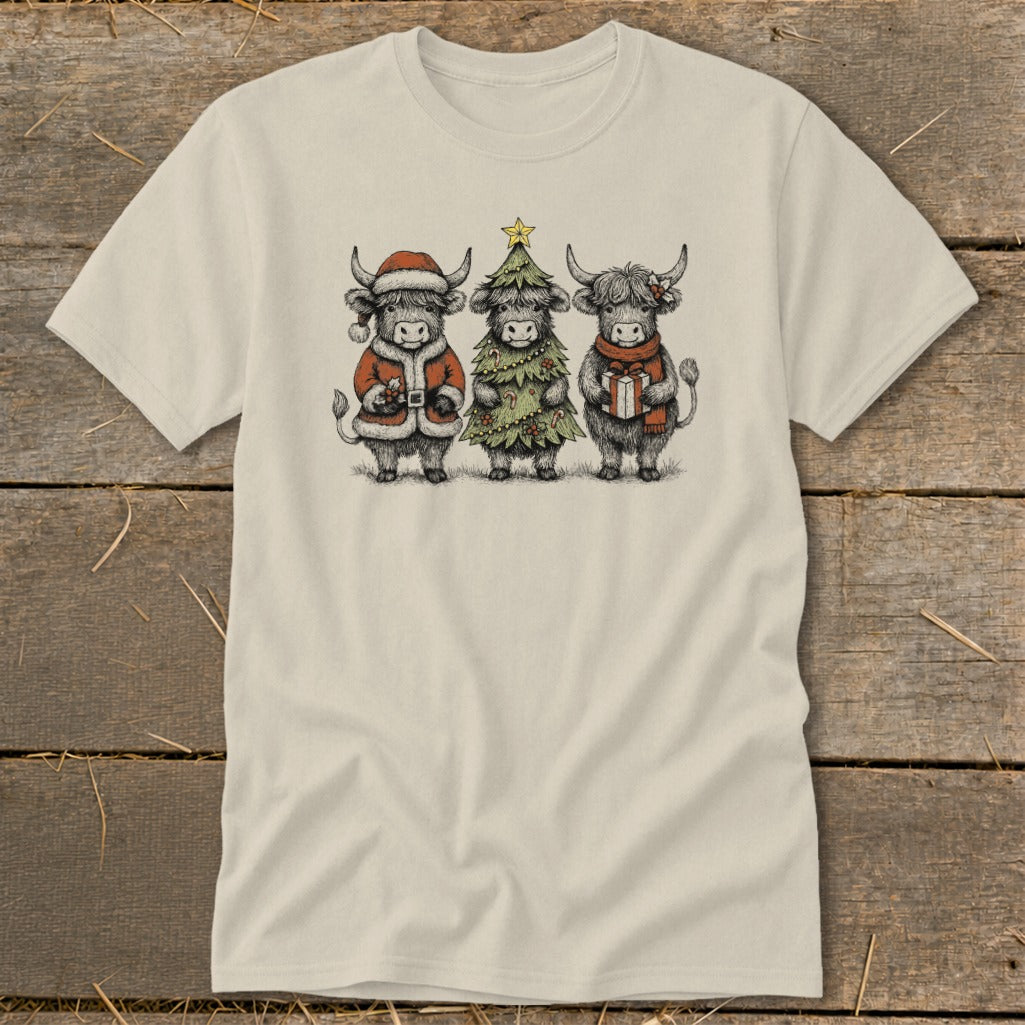 Three Highland cows dressed for Christmas, one as Santa, one as a tree, and one holding a gift.