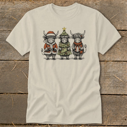 Three Highland cows dressed for Christmas, one as Santa, one as a tree, and one holding a gift.