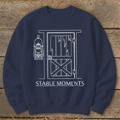 Navy sweatshirt with white line drawing of a barn door and lantern, text "STABLE MOMENTS".