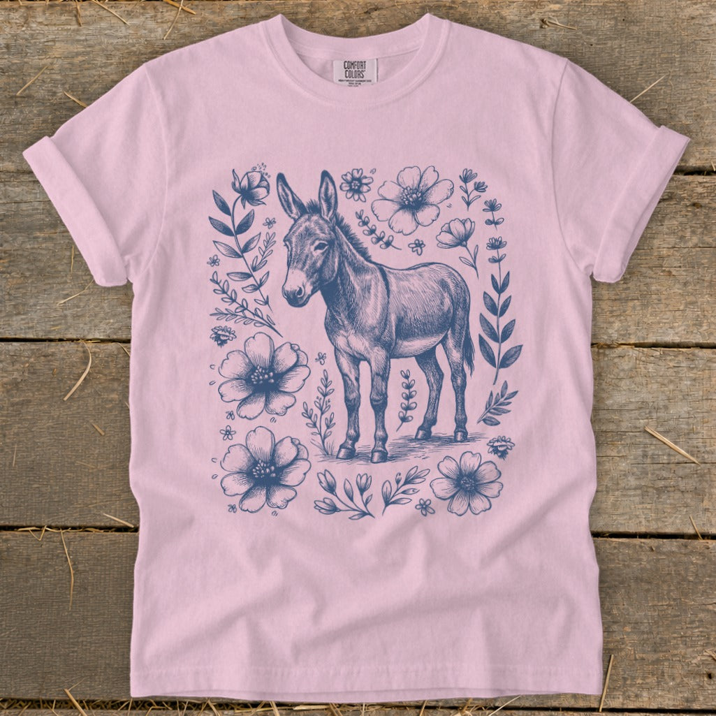 Pink t-shirt with a charcoal sketch of a donkey surrounded by flowers.